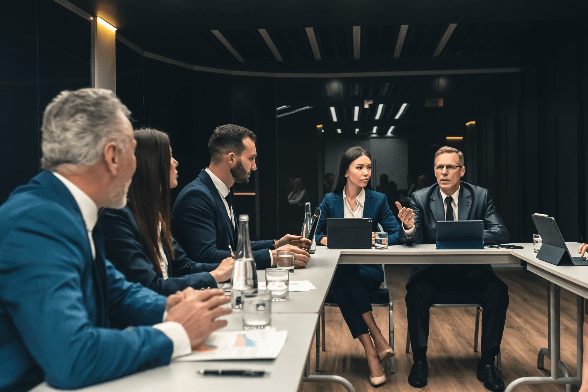 Executives reviewing material on laptops around a boardroom table