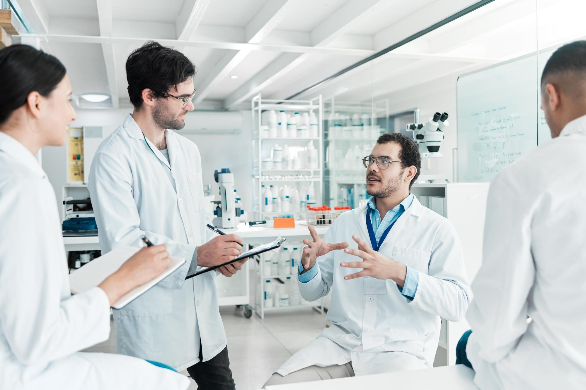 Two researchers in lab coats discussing results beside laboratory glassware