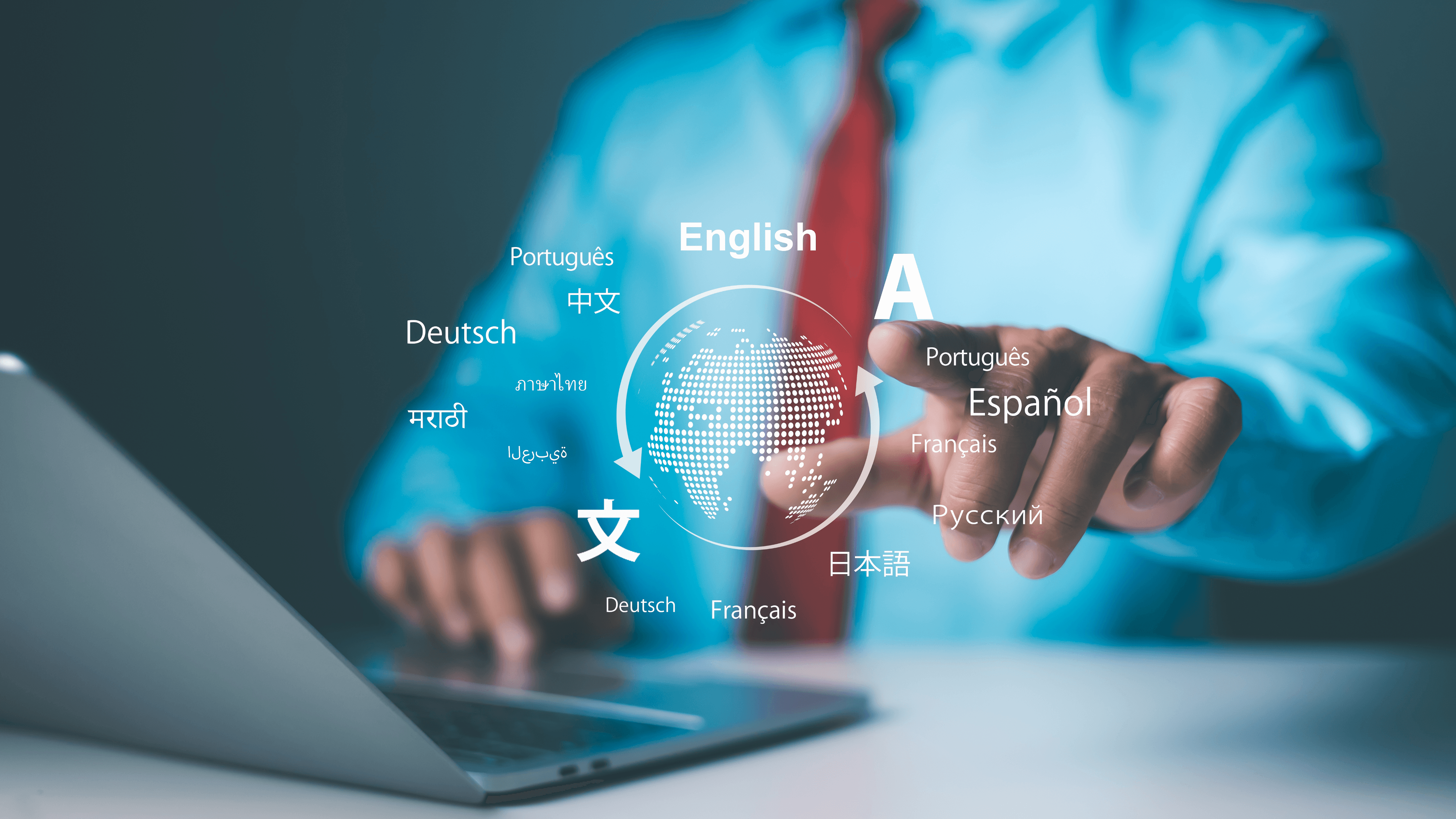 Hands typing on a laptop beside a globe surrounded by words in many languages