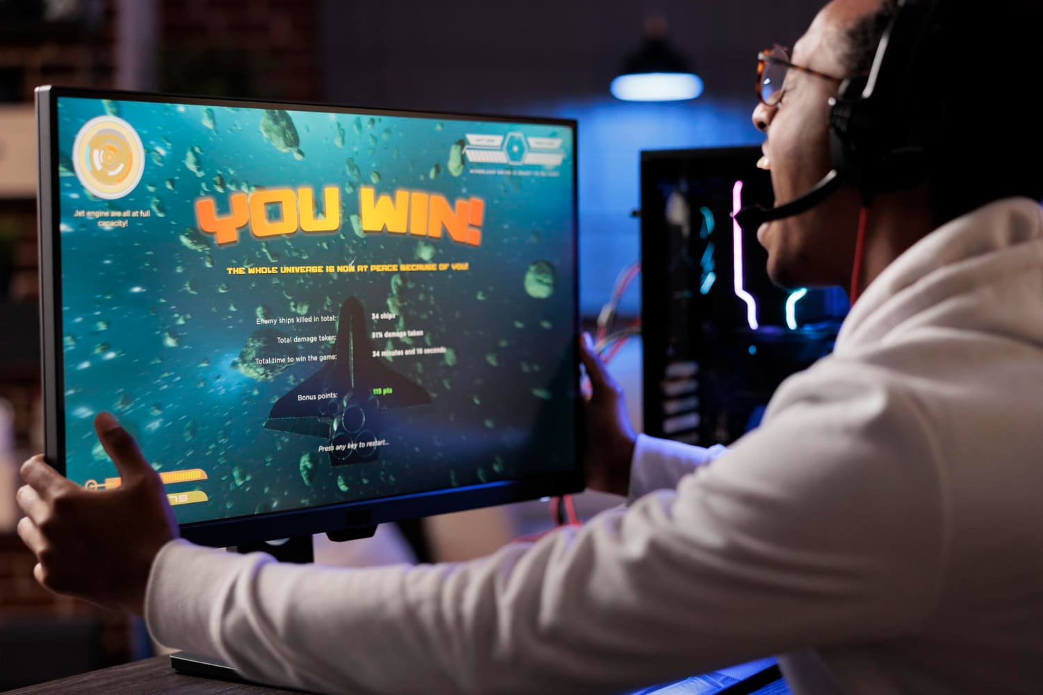 Learner at a desk facing a screen showing a gamified YOU WIN result
