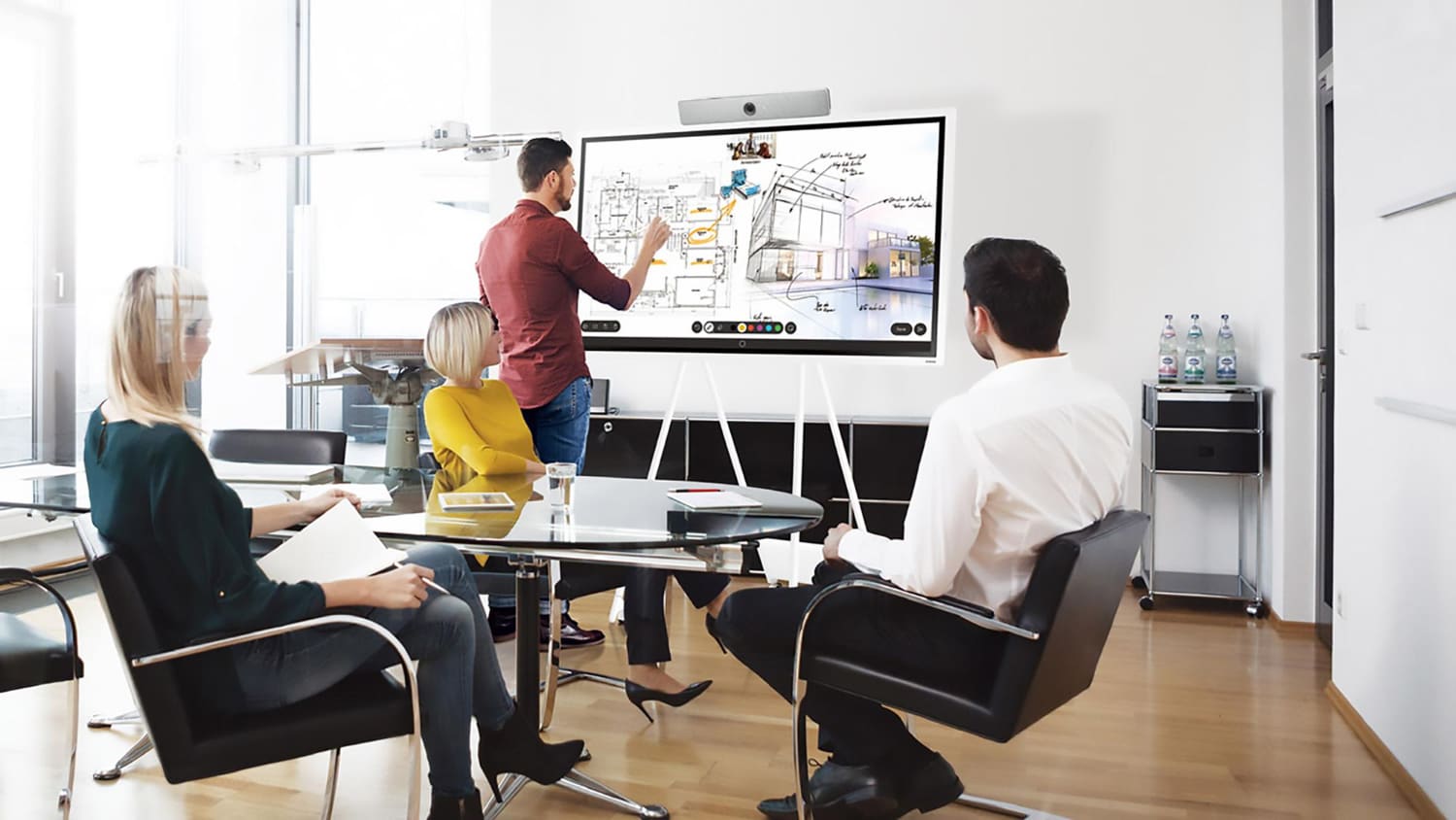 Team in a meeting room presenting on a large interactive video display screen
